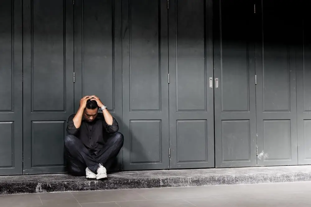A man sitting on a step with his head in his hands
