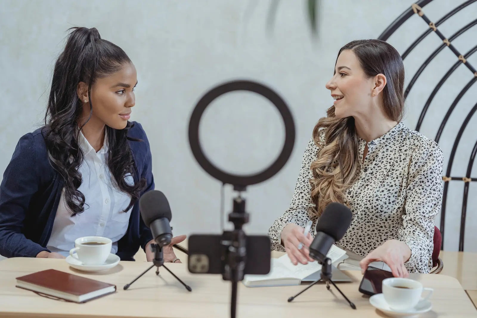 Two people recording an interview at a table with microphones