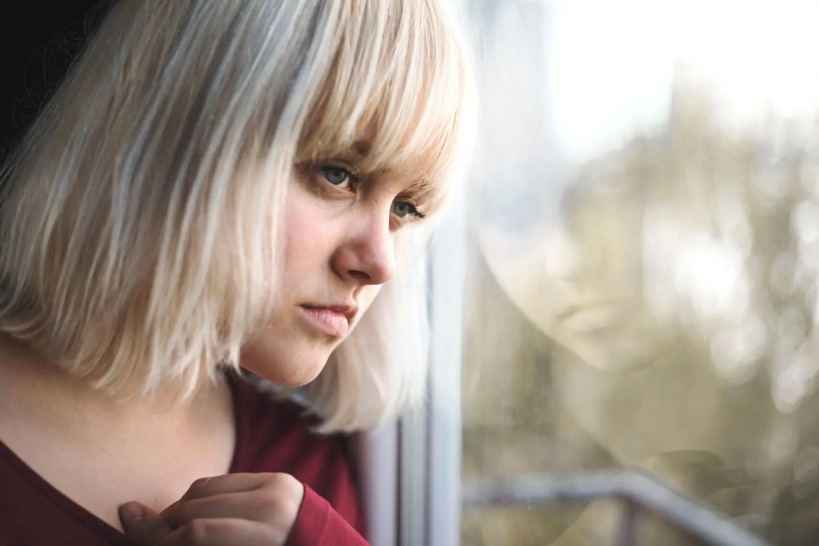 Woman looking through a window, reflecting on schizophrenia symptoms