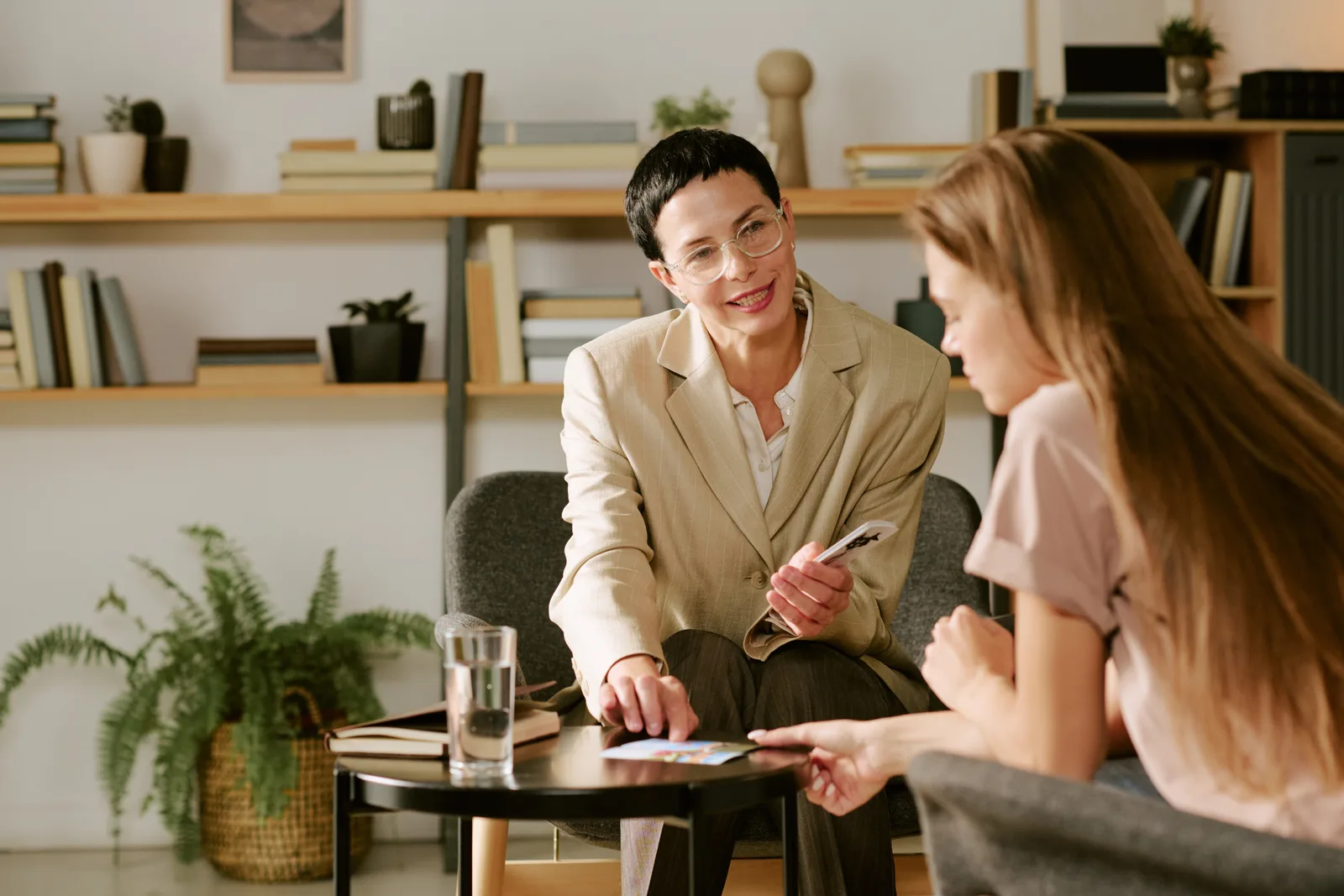 A therapist talks with a woman seated beside a small table in an office.