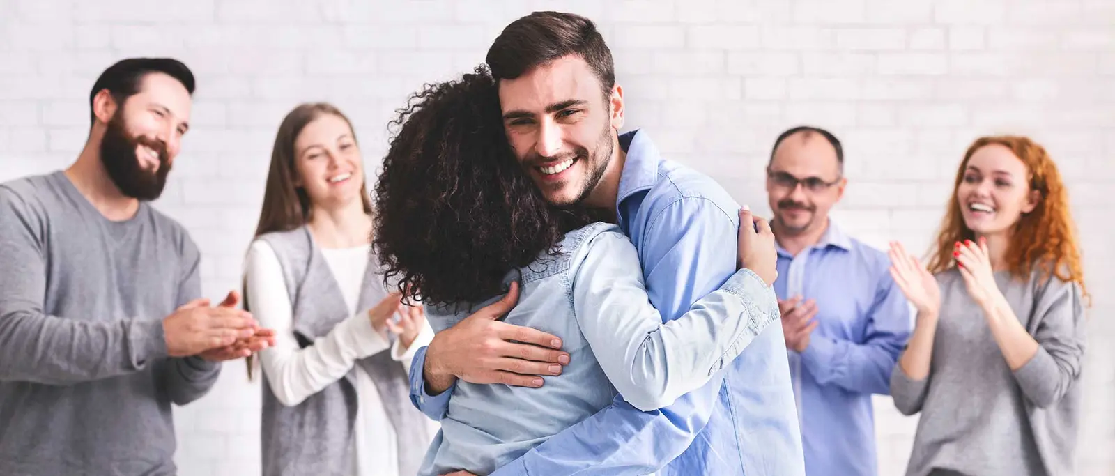 A support group congratulating a member with a hug