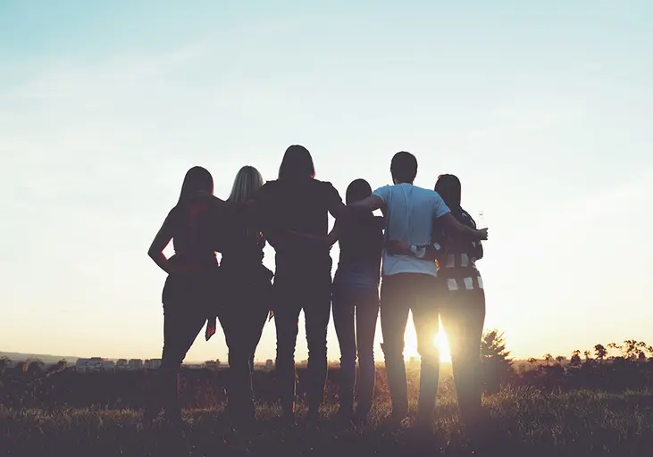 A group of friends standing together at sunset