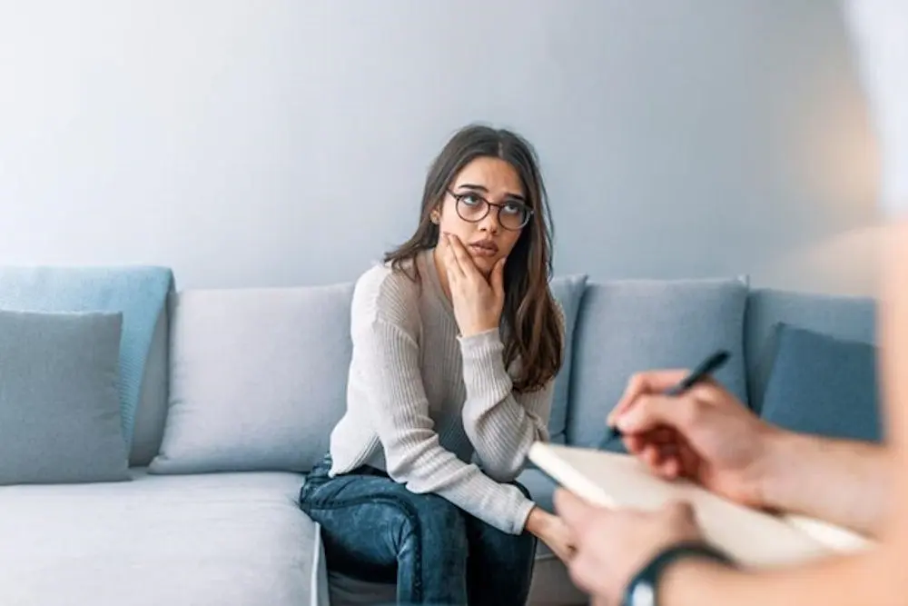 A woman conversing with a man on a couch.