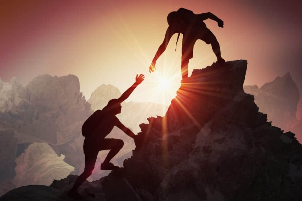 woman receiving help while climbing