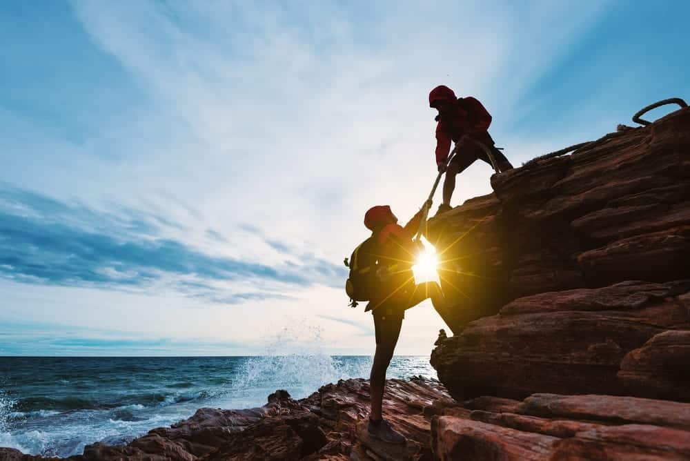 woman receiving help while climbing